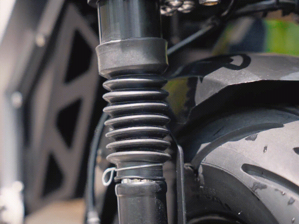 A close-up shot of an electric scooter's suspension system in motion, showcasing the robust shock absorbers and their ability to handle rough terrains.
