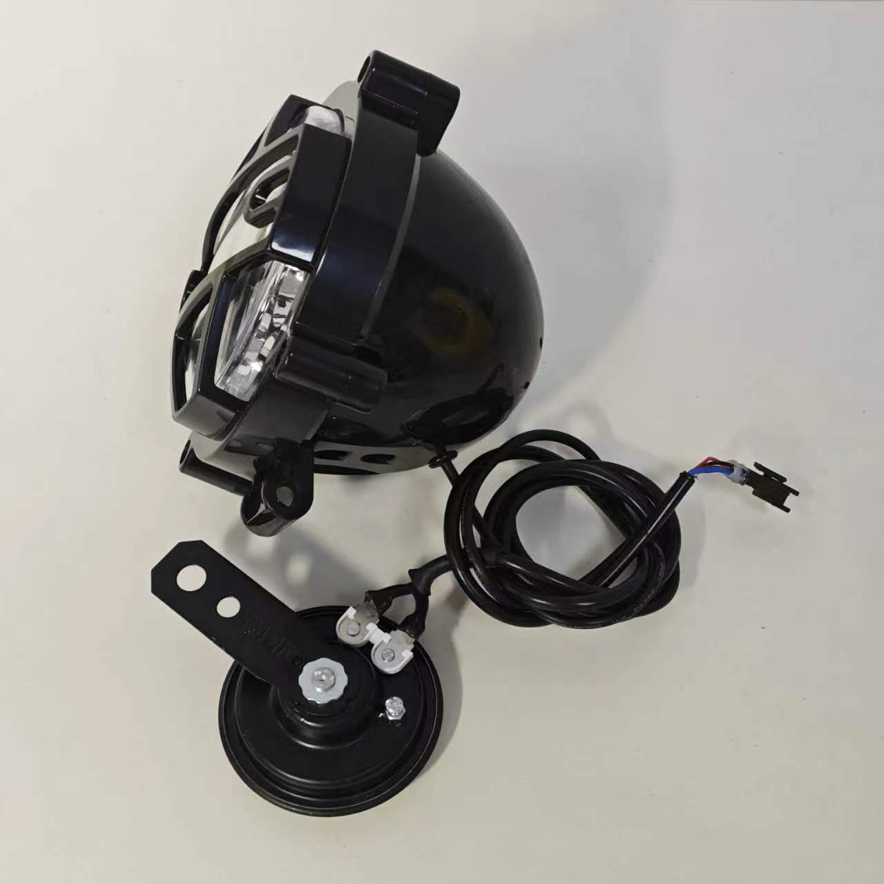 Electric motorcycle headlight and horn assembly, including wiring and mounting hardware. A horn is attached to the side to effectively warn pedestrians and other vehicles. This assembly is versatile and can be easily installed on a variety of electric motorcycles to enhance safety and functionality.