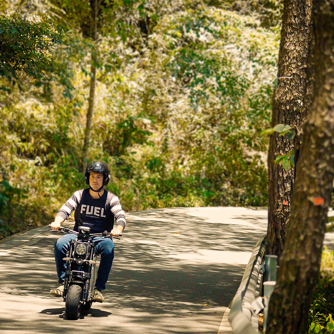 A rider on an electric motorbike cruising through a picturesque forest path, surrounded by lush greenery. The scene emphasizes the bike's suitability for leisurely rides in natural environments.