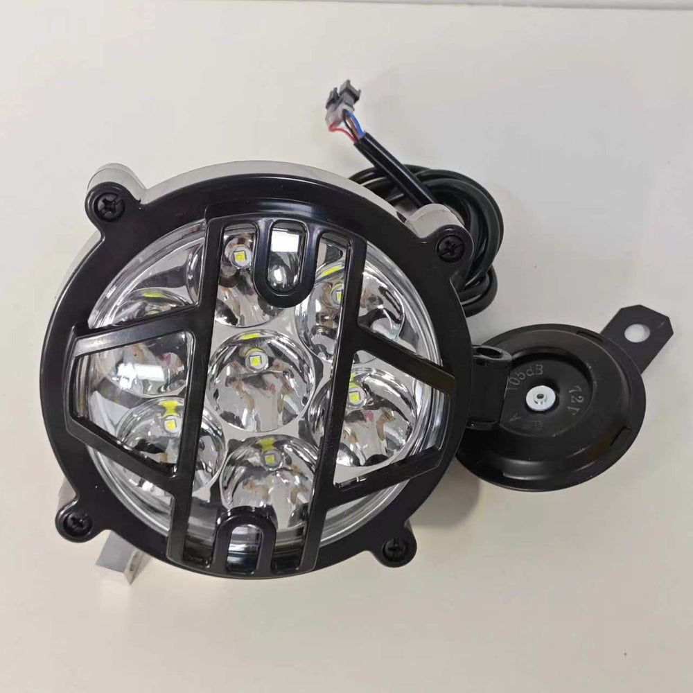 High-intensity LED headlight for electric motorcycles. The headlight is wrapped in a durable black protective grille to ensure safety while enhancing the rugged aesthetic of the vehicle. It features multiple LED bulbs configured in a circular pattern to provide a wide and bright beam, essential for enhanced nighttime visibility and road safety.
