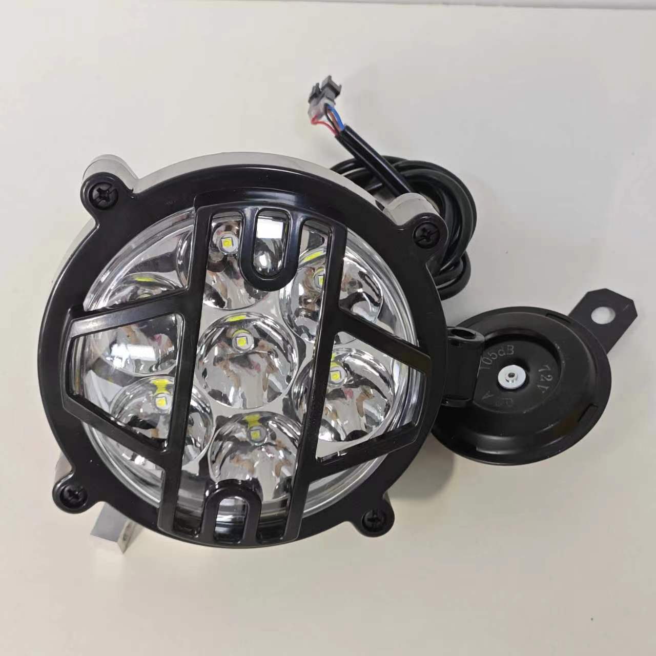 The electric motorcycle is equipped with a headlight and horn. These bulbs are arranged in a circle and are located in a solid black grille, which provides protection and creates a stylish look. A horn is mounted on the side for safety.