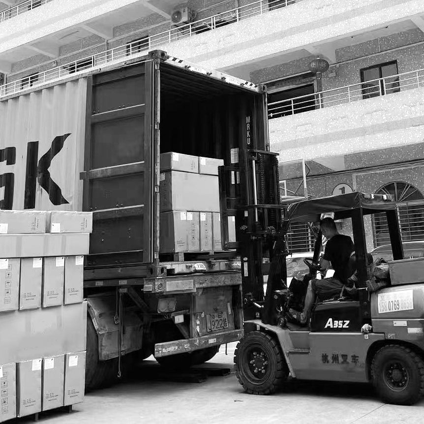 A forklift loading large boxes into a shipping container at a warehouse, illustrating the export and logistics process for electric scooters or motorbikes.