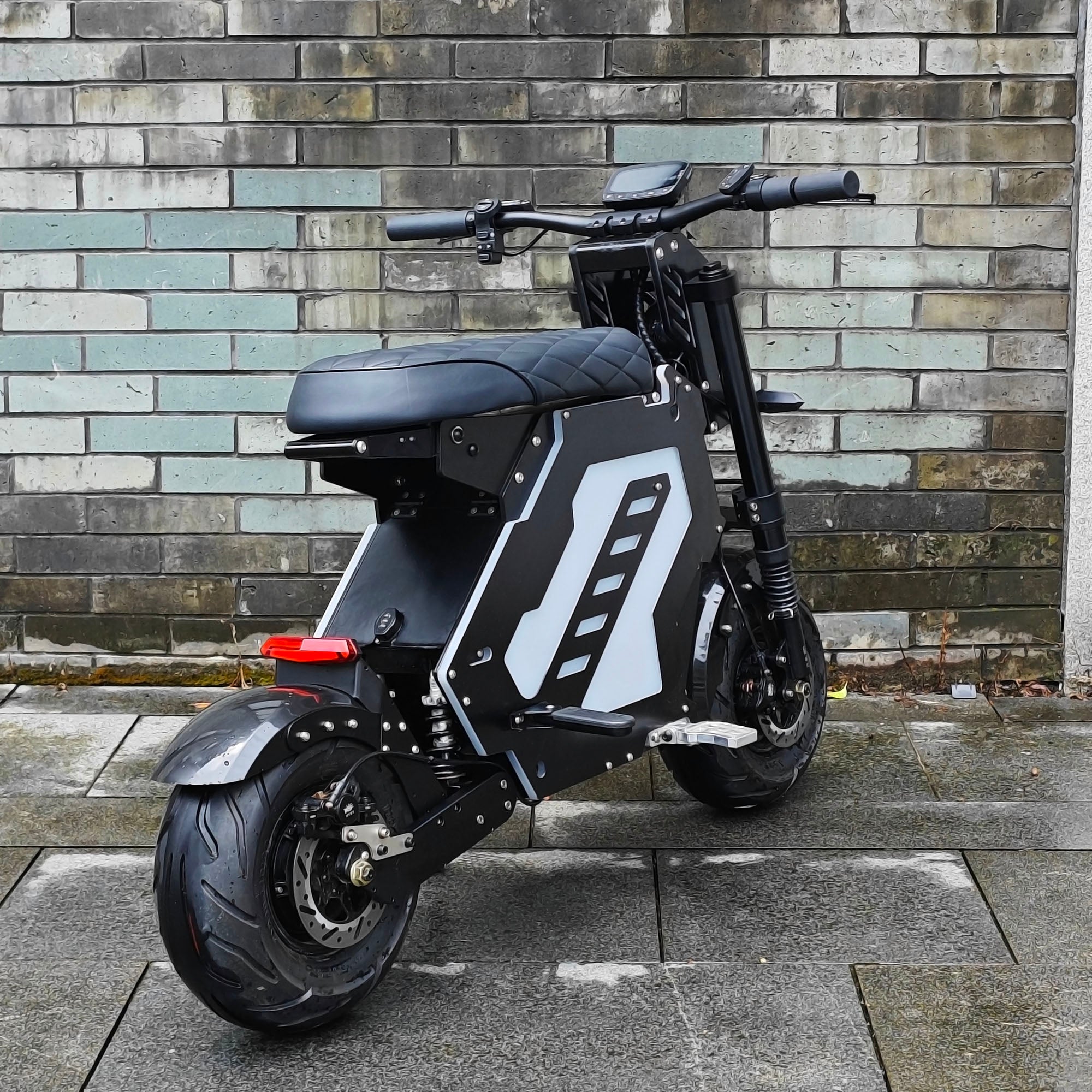 A rear view of an electric motorbike with a compact, futuristic design, parked against a brick wall. The bike features a sturdy build and sleek lines, ideal for urban mobility.